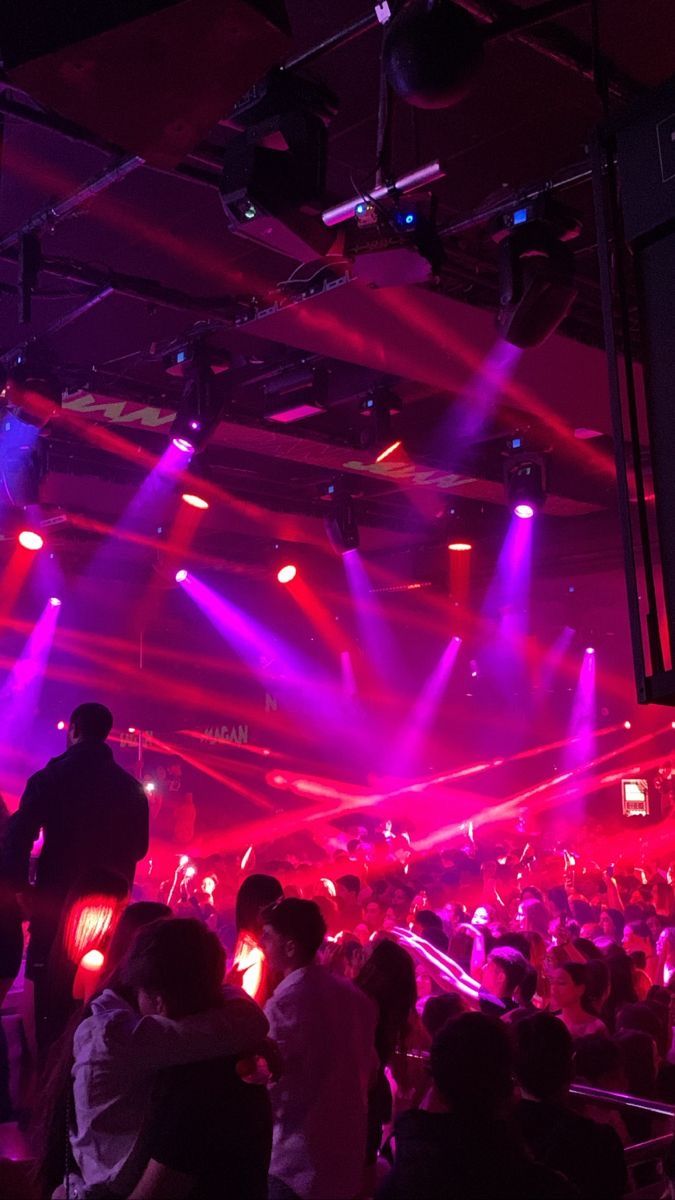 a large group of people in a room with purple and red lights