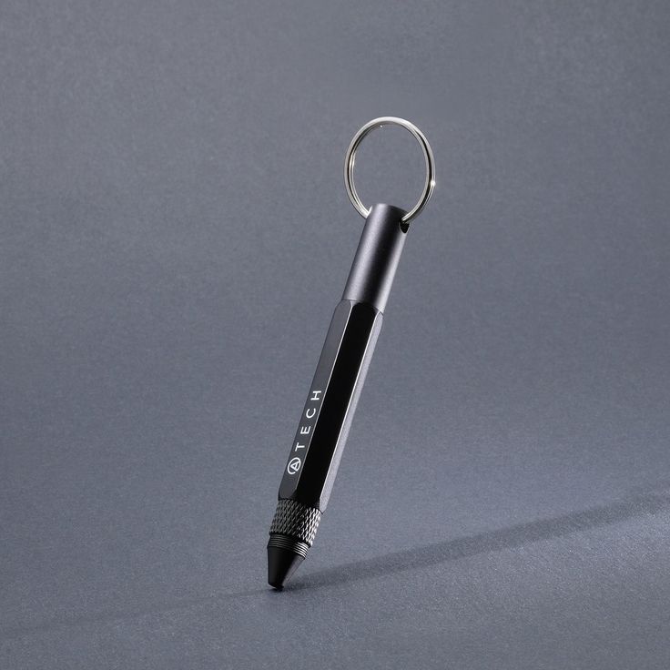 a black and silver pen is sitting on a gray surface with a keychain