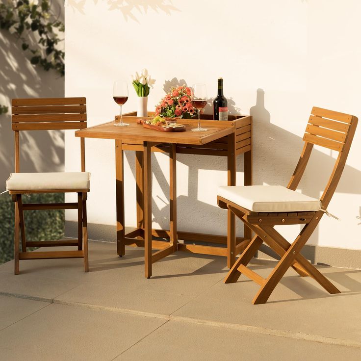 a wooden table with two chairs and a bottle of wine on the table next to it