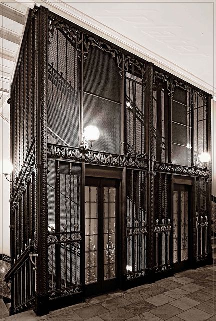 an old fashioned building with glass doors and wrought iron railings on the outside wall