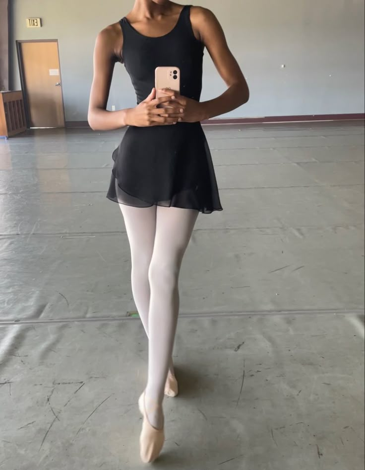 a young ballerina is holding her cell phone