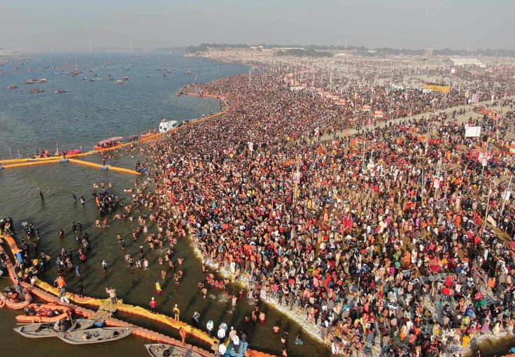 an aerial view of a large group of people gathered at the edge of a body of water