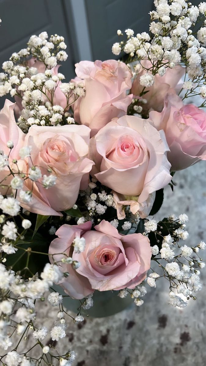 a vase filled with pink roses and baby's breath