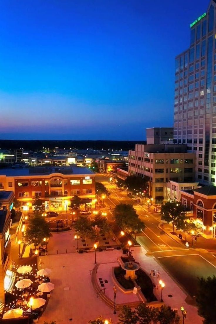 an aerial view of a city at night with lights on and buildings lit up in the background