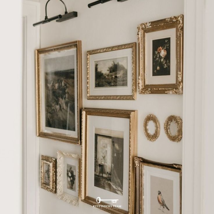 there are many framed pictures on the wall in this room with white walls and gold trim