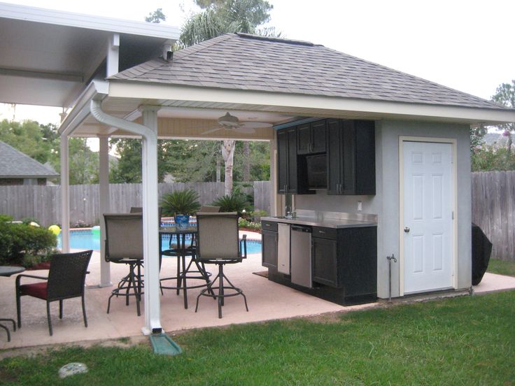 an outdoor kitchen and dining area in a backyard