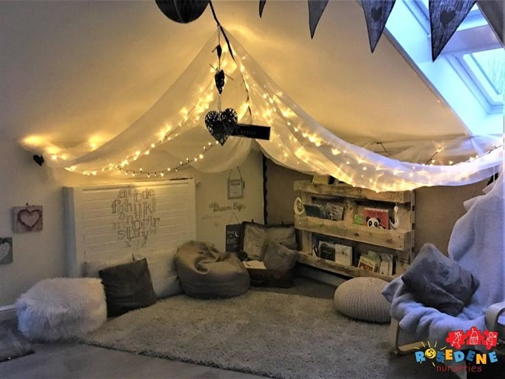 a bedroom with lights strung from the ceiling and pillows on the floor in front of it