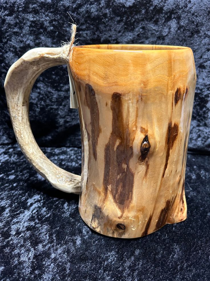 a coffee mug made out of wood on a black surface with the handle pulled back