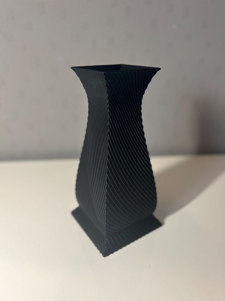 a black vase sitting on top of a white table