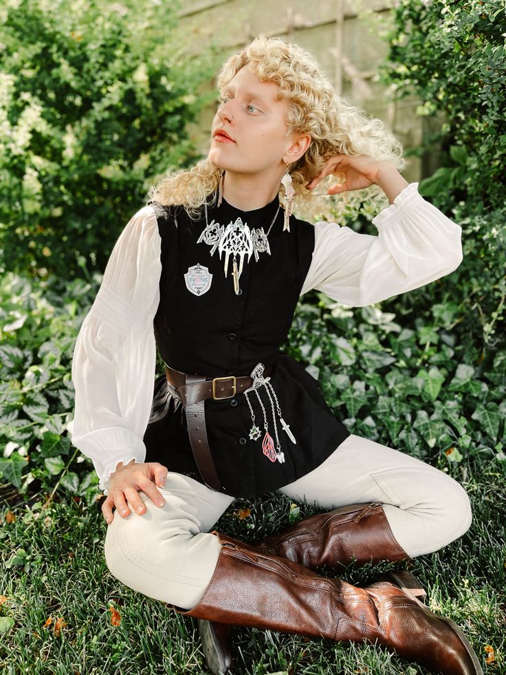 a woman sitting on the ground wearing boots and a black shirt with white writing on it