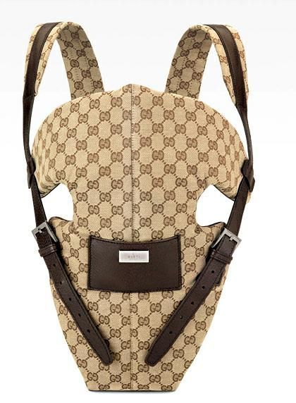 the back of a baby carrier in beige and brown gg fabric with leather straps