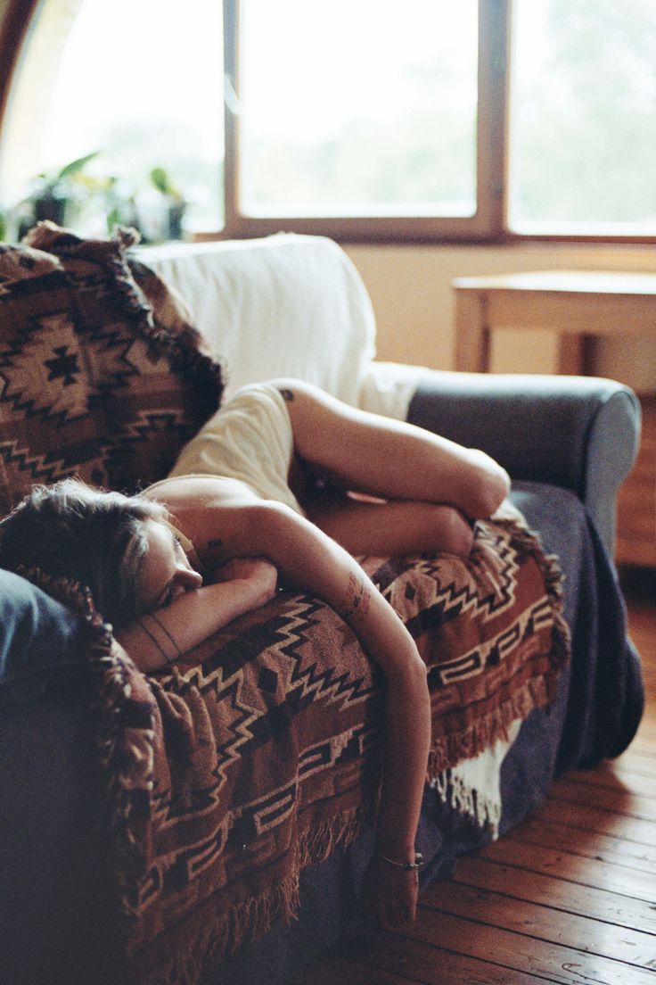 a woman laying on top of a couch next to a window