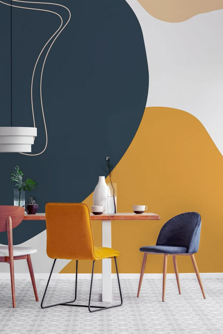 two chairs sitting at a table in front of a wall with an abstract design on it