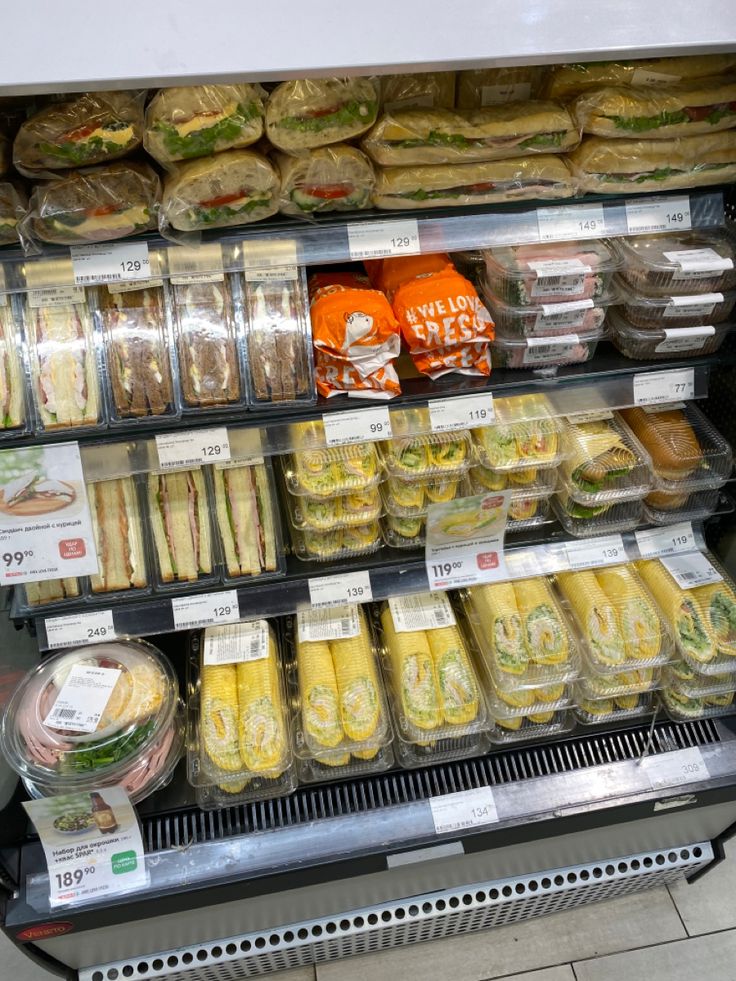 a display case filled with lots of sandwiches and other foods in plastic wrapper containers