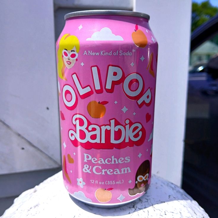 a pink can of lippop barbie peaches and cream on a white table outside