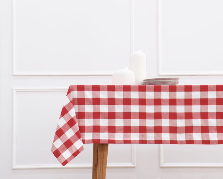 a red and white checkered table cloth on a wooden chair next to a candle