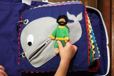 a person holding a stuffed animal in front of a blue bag with a whale on it