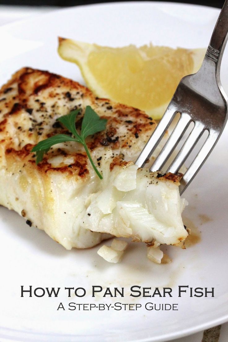 a white plate topped with fish next to a lemon wedge on top of a fork