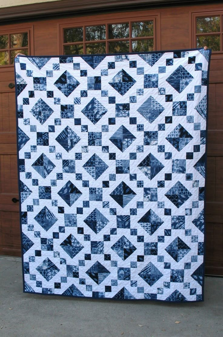 a large blue and white quilt sitting in front of a garage door