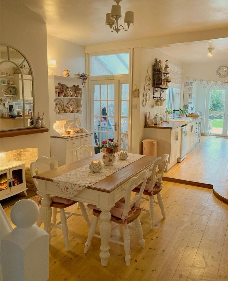 a dining room table and chairs in front of an open kitchen with wooden flooring