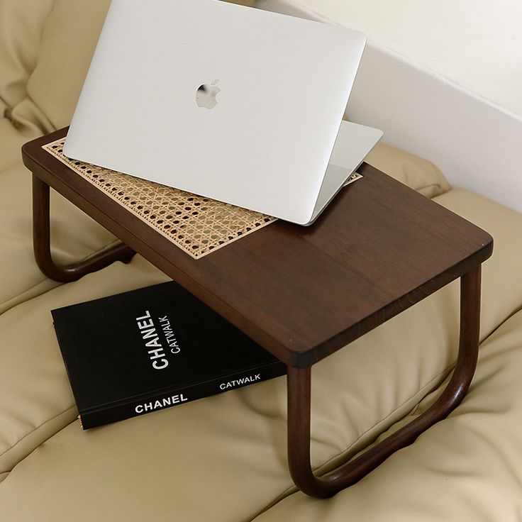 a laptop computer sitting on top of a wooden table next to a black and white book