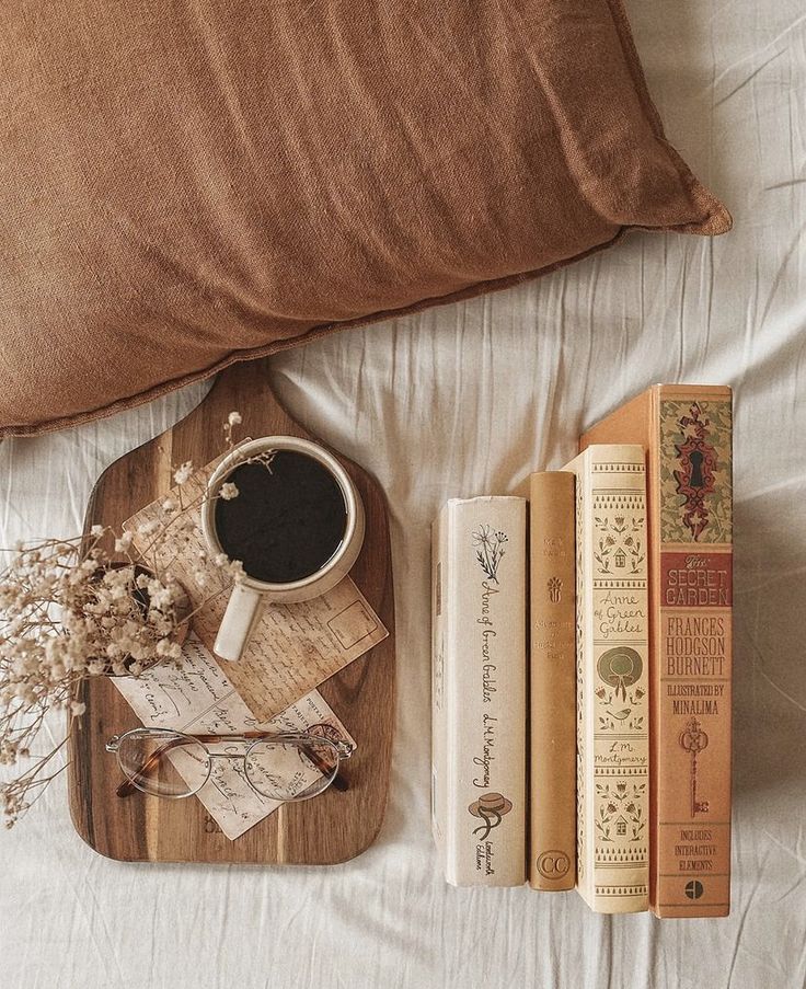 some books are laying on a bed with a cup of coffee and two bookends