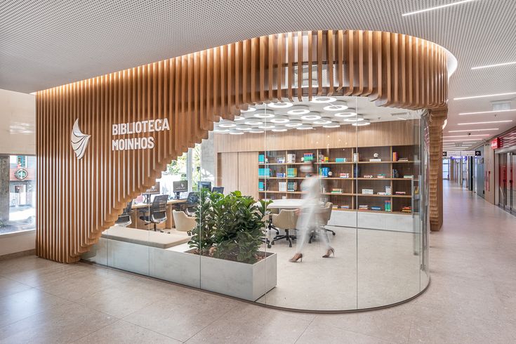 an office with circular wooden partitions in the center and plants on tables at the end