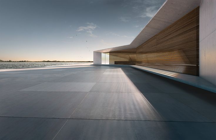 an empty concrete walkway next to a body of water with the sun shining on it