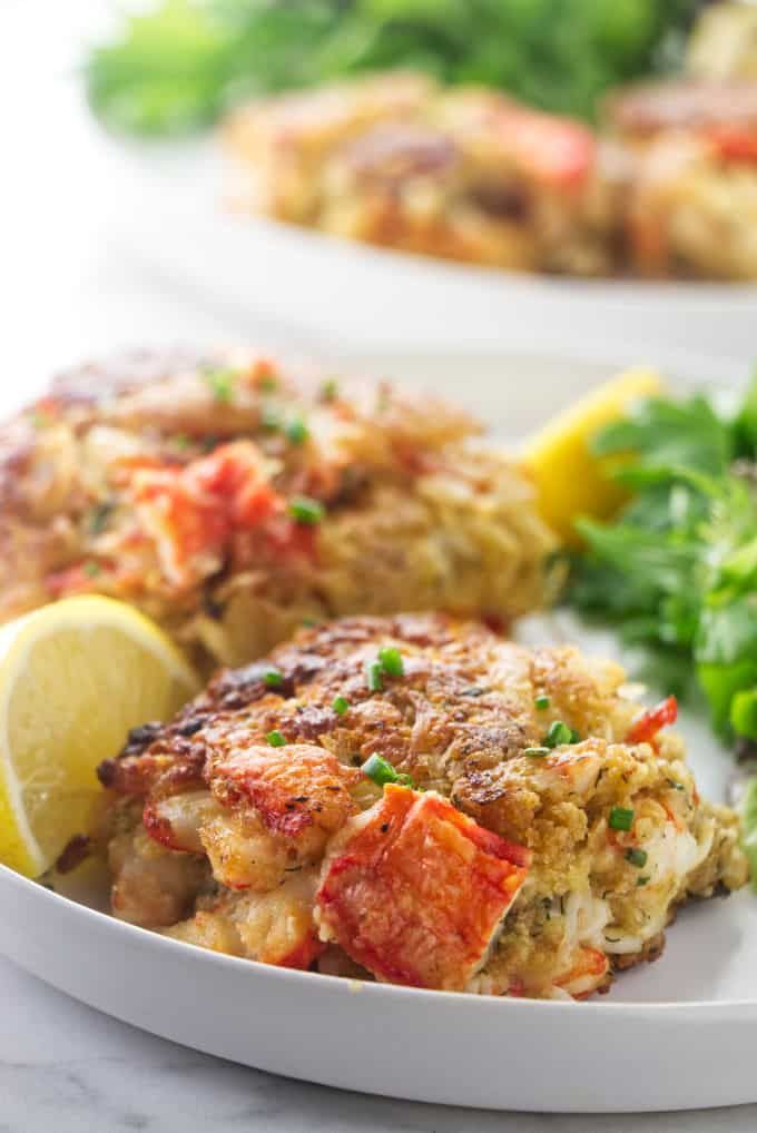 crab cakes on a plate with lemon wedges and parsley garnishes