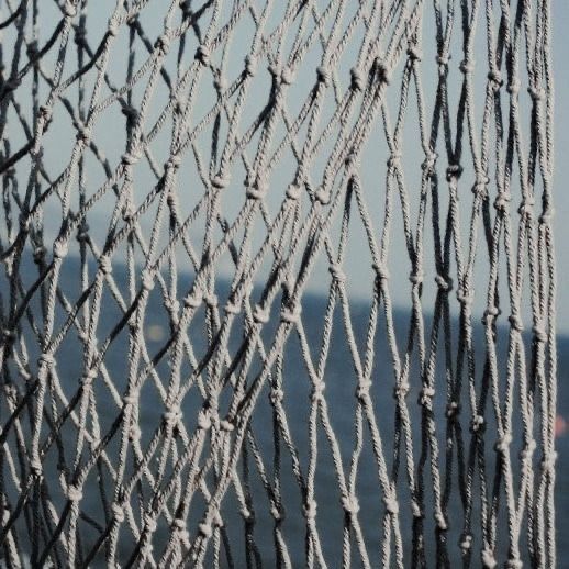 a close up view of a net with rope on the water in the back ground