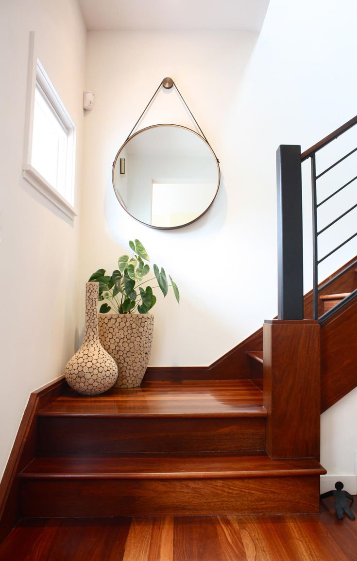 two vases with plants sit on the stairs next to a mirror and door way