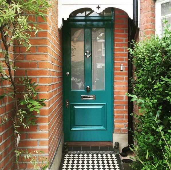 a green door in front of a red brick house with black and white checkered floor