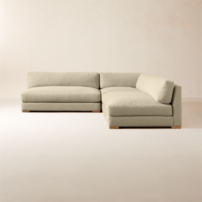 a white sectional couch sitting on top of a wooden floor next to a beige wall