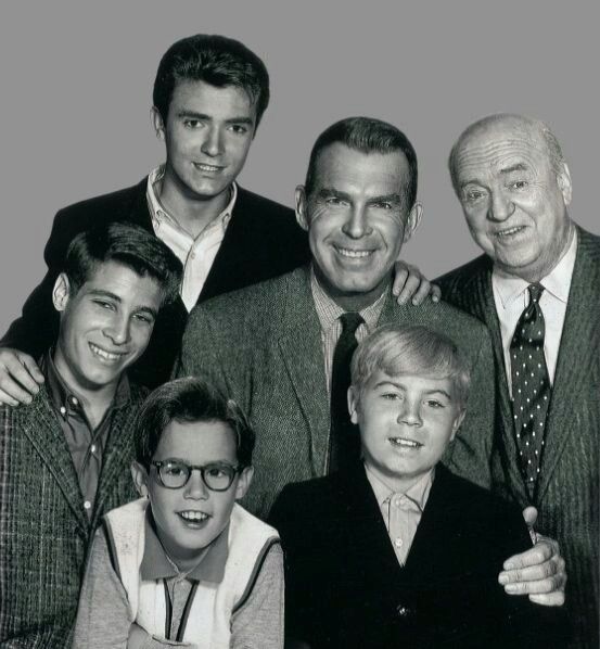 an old black and white photo of people posing for a group shot with one man in the middle