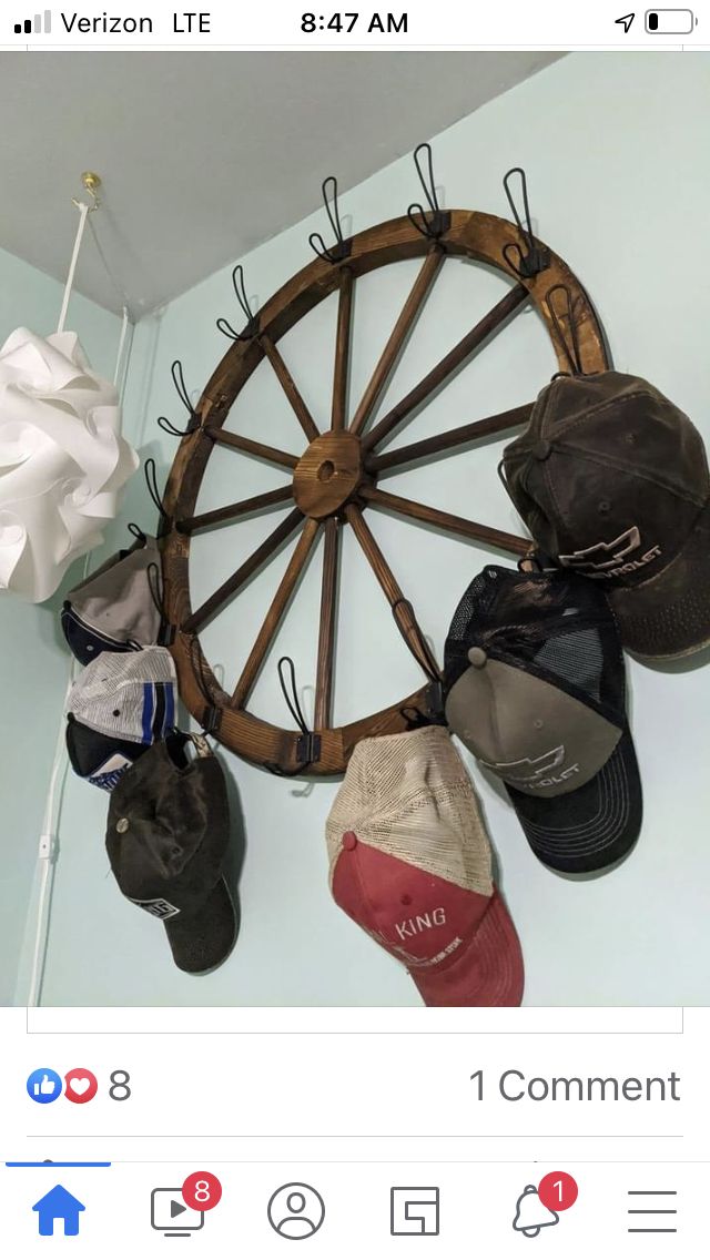 several hats are hanging on a wall with a wheel in the middle and other items below