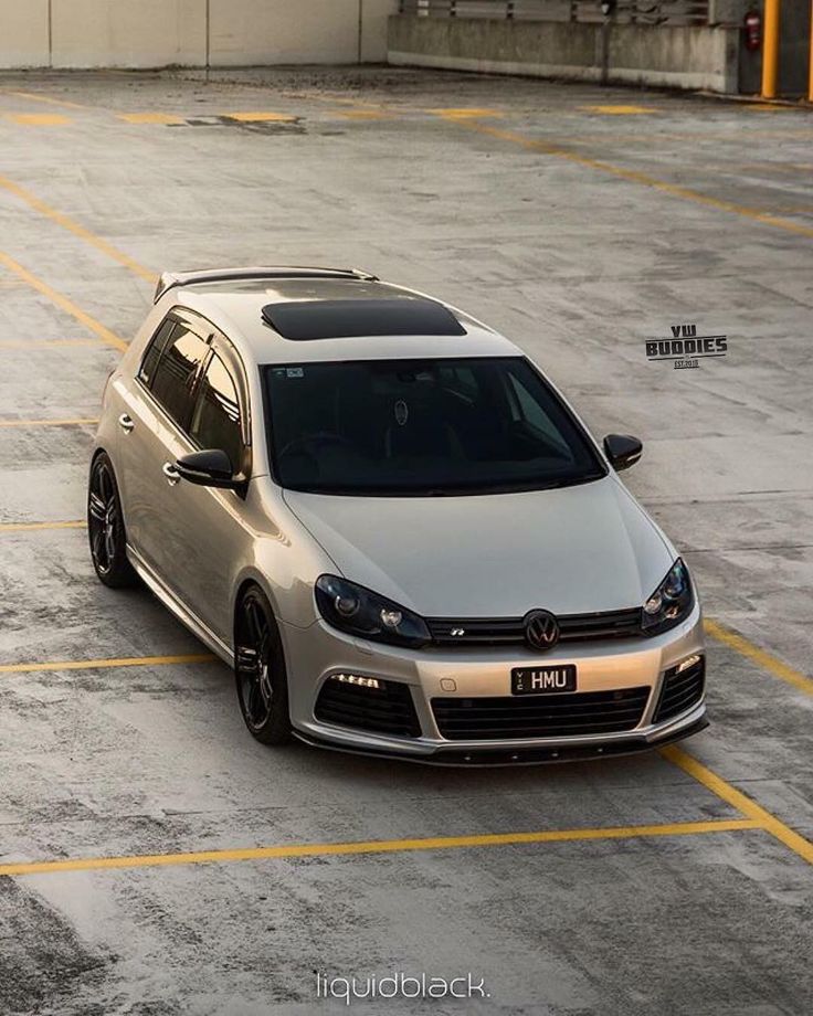 a silver car is parked in an empty parking lot with yellow lines on the ground