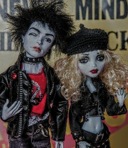 two dolls dressed in black and red standing next to each other