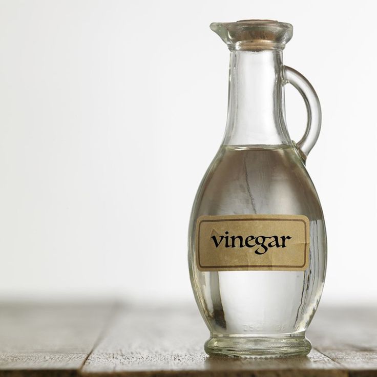 a glass bottle filled with vinegar sitting on top of a wooden table