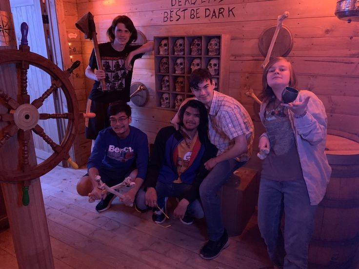 some people are posing for a photo in front of an old ship's wheel