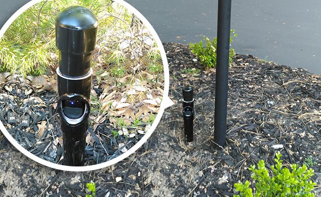 there are two black poles in the ground next to each other and one pole has an upside down camera on it