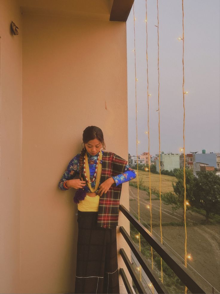 a woman standing on a balcony next to a building