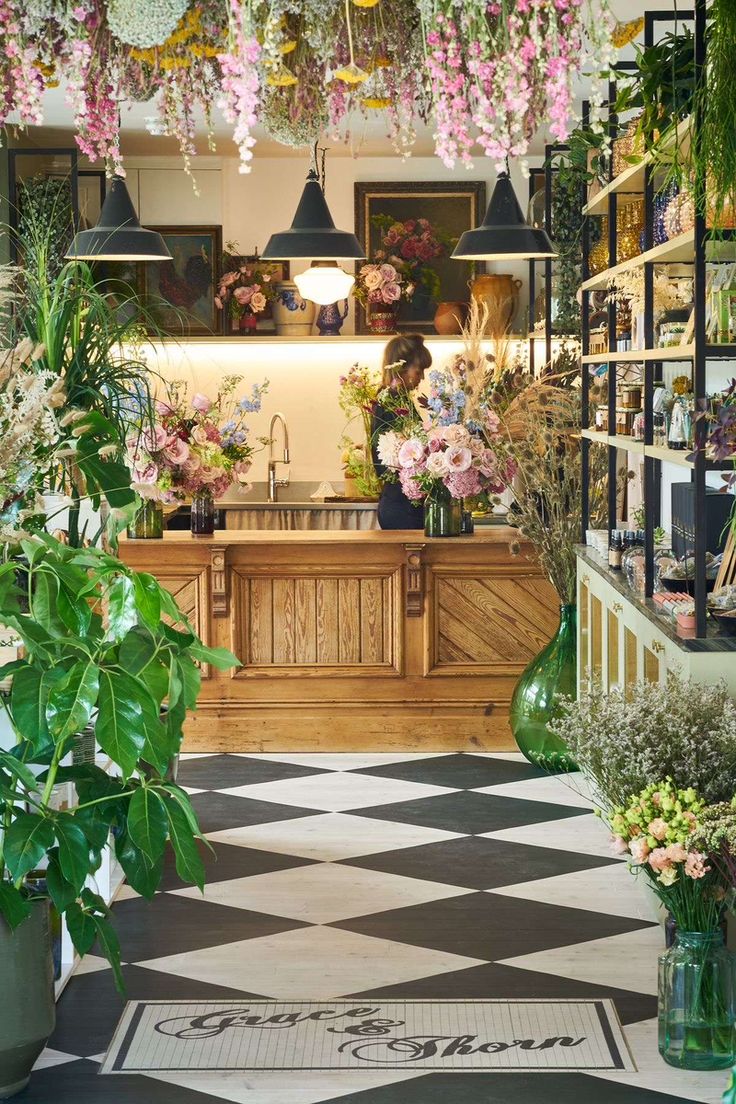 a flower shop filled with lots of flowers and greenery next to a counter top