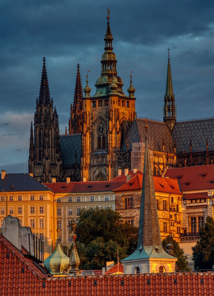 an old city with many spires and buildings in the foreground, under a cloudy sky