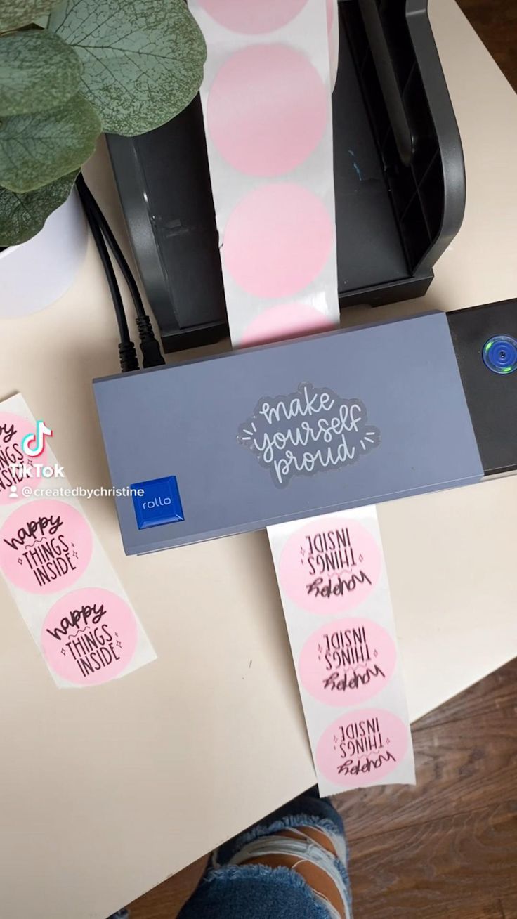 some pink and white stickers sitting on top of a desk next to a printer