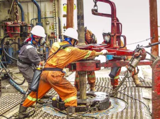 two men in safety gear working on an oil rig