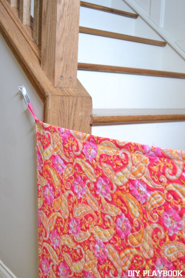 an orange and pink quilt hanging from a wooden banister