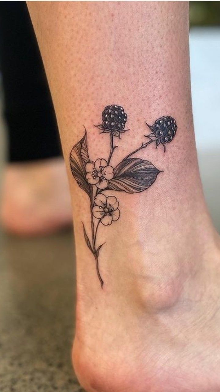 a small flower tattoo on the ankle that is sitting on a woman's leg