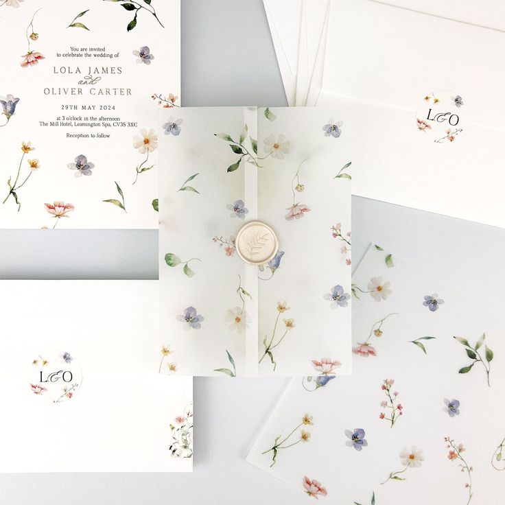 the wedding stationery is laid out on top of each other, with floral designs