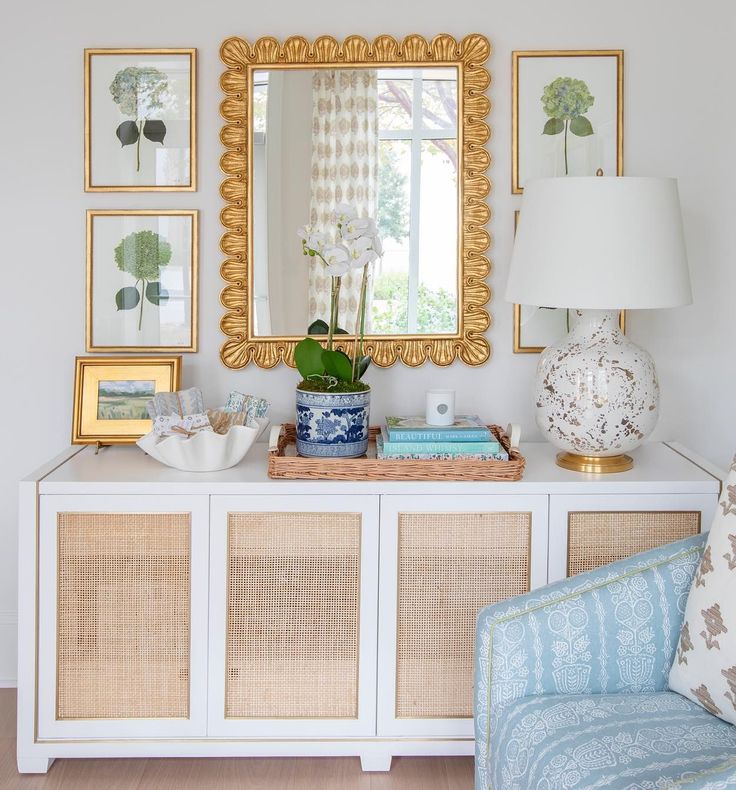 a white dresser topped with a blue and white chair next to a wall mounted mirror