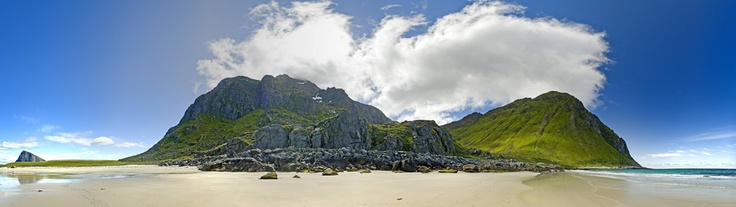 a sandy beach with mountains in the background